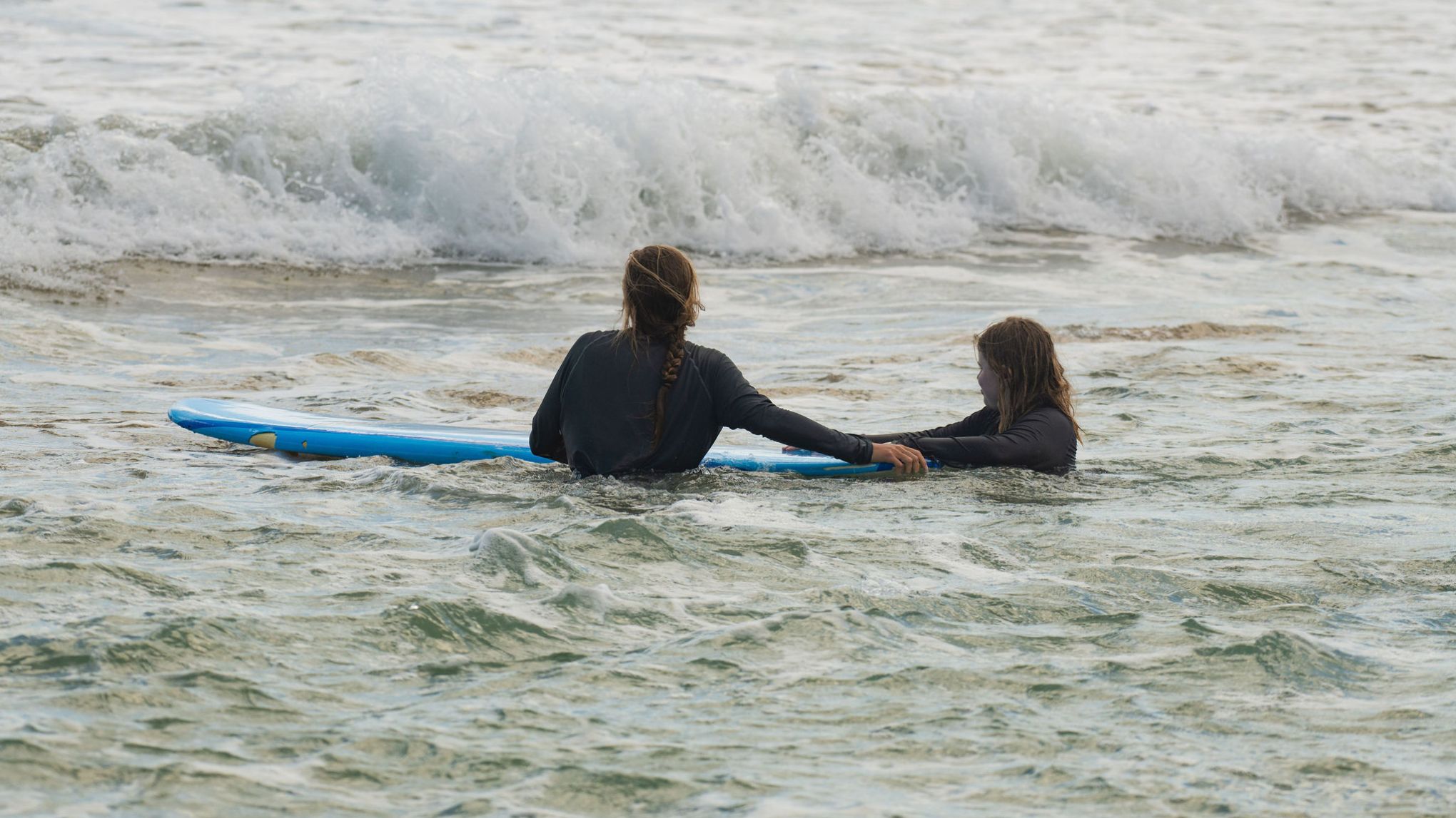 a young girl riding a wave on a surfboard in the water
