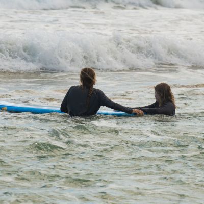 a young girl riding a wave on a surfboard in the water
