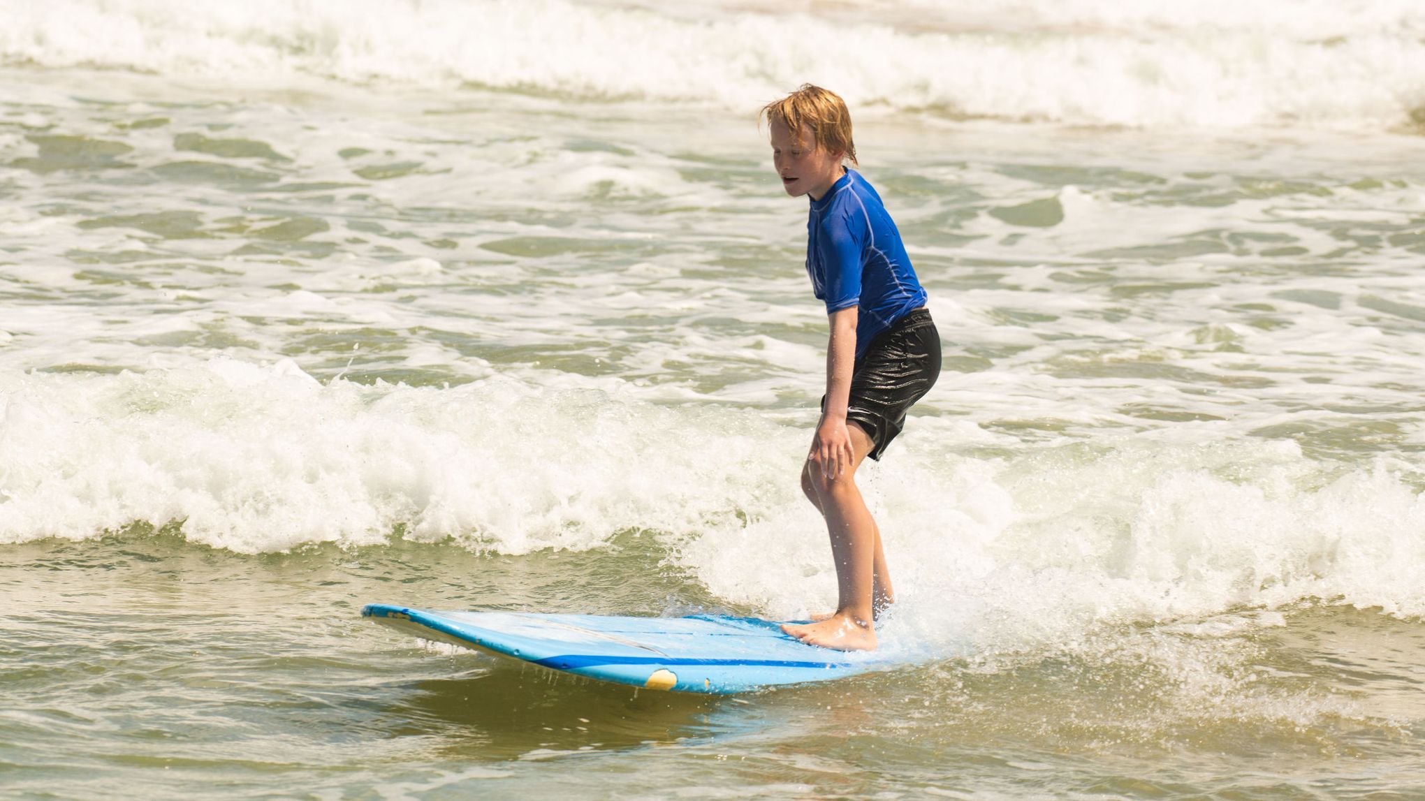 a young girl riding a wave on a surfboard in the ocean