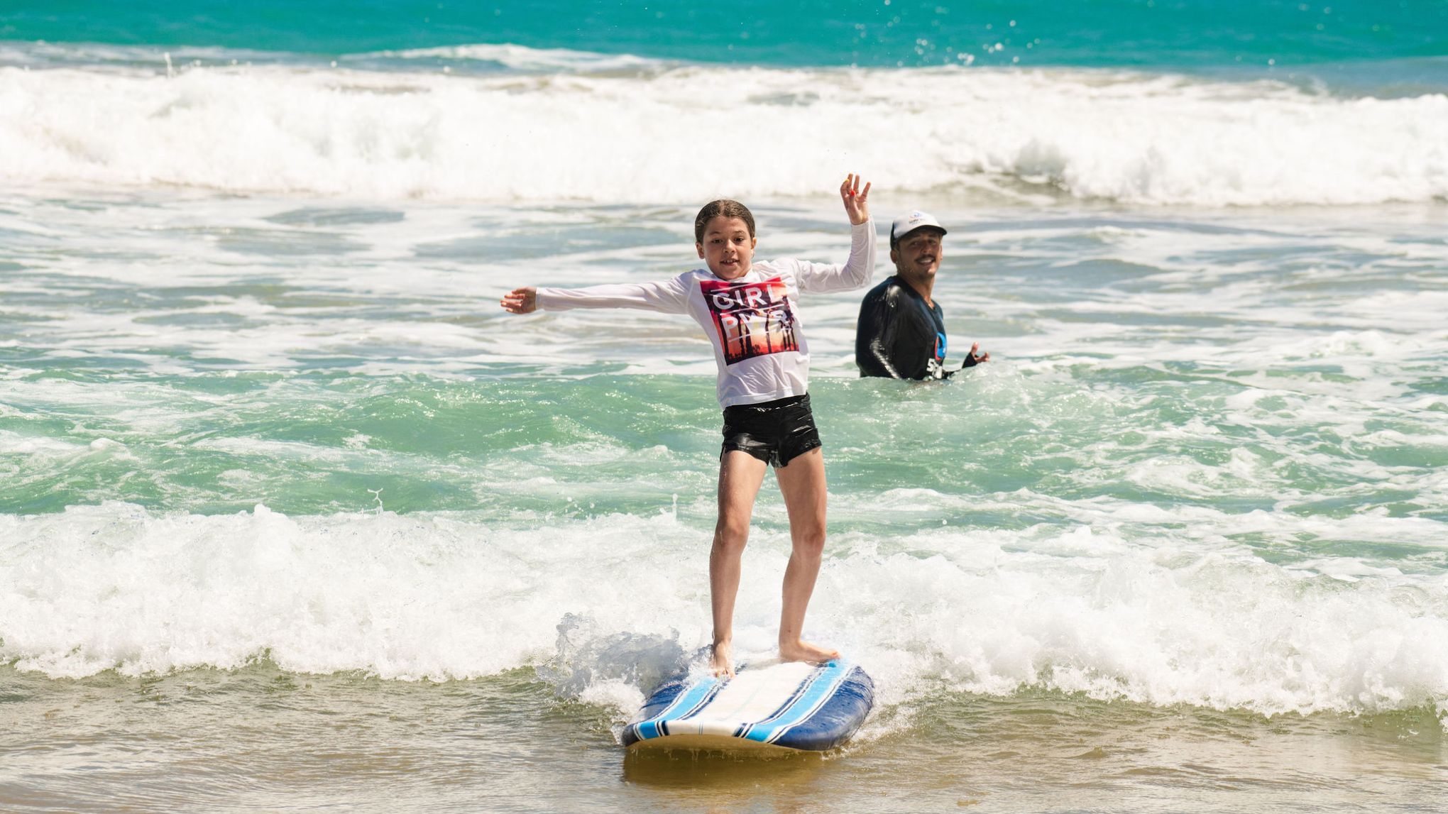 a young girl riding a wave on a surfboard in the ocean