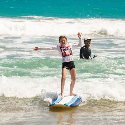 a young girl riding a wave on a surfboard in the ocean
