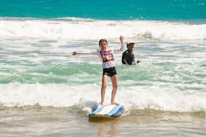 a young girl riding a wave on a surfboard in the ocean