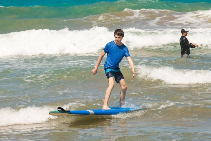 a small girl riding a wave on a surfboard in the ocean