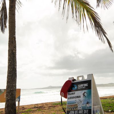 a sign on a beach with a palm tree